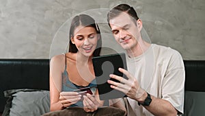 Young couple sit in the bed room using online payment app. Adit