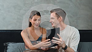 Young couple sit in the bed room using online payment app. Adit