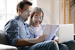 Young couple sit on couch paying bills online