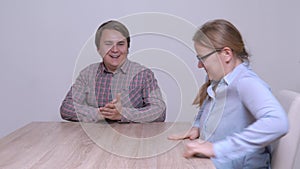 Young couple sit down at table for peace talks or marital psychological therapy. Man and woman run their hands and smile