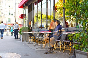 Young couple sit in Parisian cafe