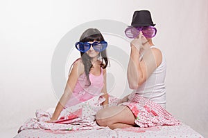 Young couple sitting bed with big glasses, guy in hat