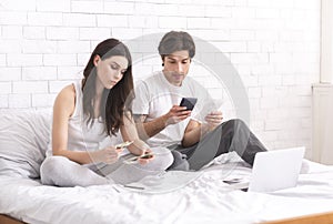 Young couple sitting on bed at home and checking finances