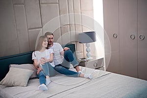 Young couple sitting on bed with pillows photo