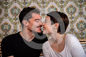 Young couple is sitting on the bed and using the computer.