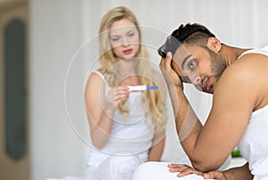 Young Couple Sitting In Bed, Woman Show Man Positive Pregnancy Test Conflict Relationships Problem