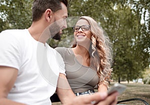 Young couple sitting on a bench in a city Park.