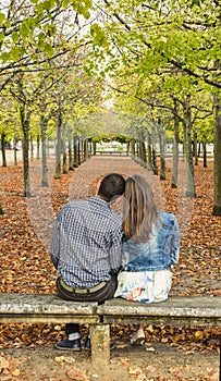 Young Couple Sitting on a Bench in a Park in Autumn