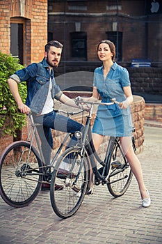 Young couple sitting on a bicycle opposite city