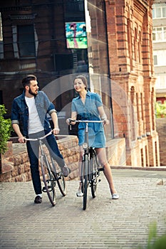 Young couple sitting on a bicycle opposite city