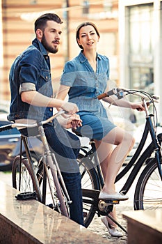 Young couple sitting on a bicycle opposite city