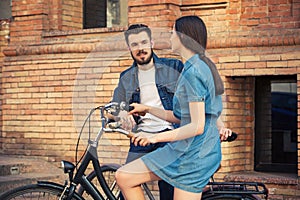 Young couple sitting on a bicycle opposite city