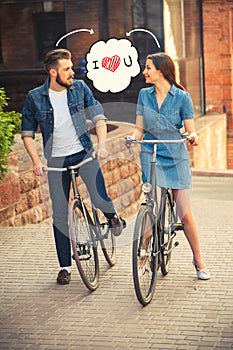 Young couple sitting on a bicycle opposite city