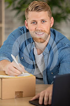young couple sitting between boxes and using laptop