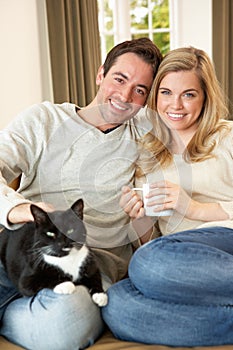 Young couple sitting with cat on sofa