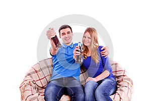 Young couple sitting on a couch and drinking a soda