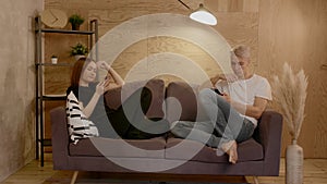 Young couple sitting on the couch. Guy and a girl look at their phones