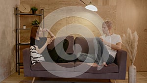 Young couple sitting on the couch. Guy and a girl look at their phones