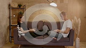 Young couple sitting on the couch. Guy and girl working on laptops