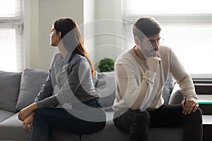 Young couple sitting on couch separately from each other