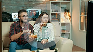 Young couple sitting on the couch and watching television