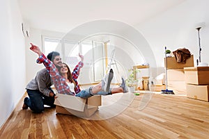 Young couple sitting on the floor of empty apartment. Move in to new home.