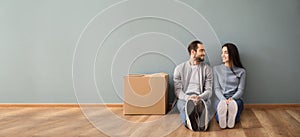 Young couple sitting on floor near box indoors. Moving into new house