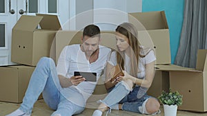 Young couple sitting on floor using tablet computer after reloction in their new home