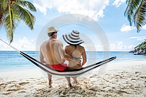 Young Couple Sitting On Hammock At Beach