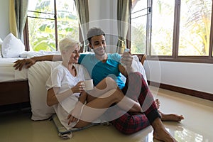 Young Couple Sitting Near Bed, Morning Happy Smile Hispanic Man And Woman Using Cell Smart Phone