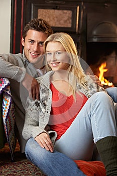 Young couple sitting by open fire