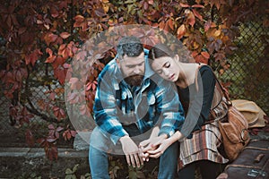Young couple sitting outdoors at the park on beautiful autumn day. Adventure, travel, tourism, hike and people concept -