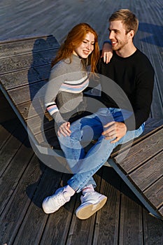 young couple are sitting in the park on a wooden bench hugging