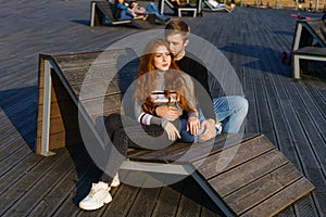 young couple are sitting in the park on a wooden bench hugging