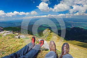 Young couple sitting on the peak enjoying valleys and mountains