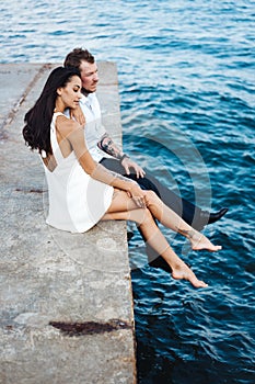 Young couple are sitting on the pier by the sea