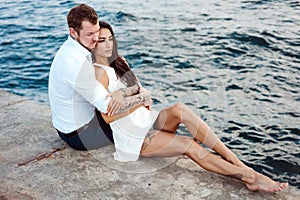 Young couple are sitting on the pier by the sea