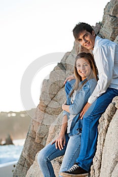 Young couple sitting on rocks at seaside.