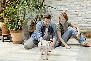 Young couple sitting at rustic living room floor and playing with dog