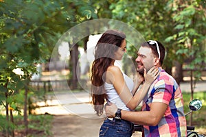 Young couple sitting on a scooter and talking in a city park