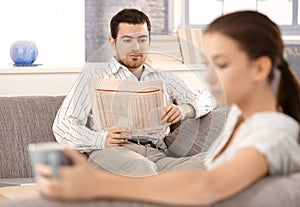 Young couple sitting separated in living room