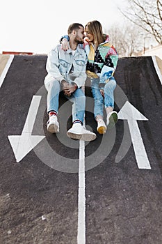 Young couple sitting between the signs on the floor of a skate park