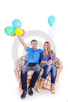 Young couple sitting on a sofa with balloons