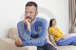 Young couple sitting on sofa being angry after fight. Couple Having Argument At Home. Girlfriend and boyfriend sitting next to