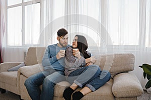 Young couple sitting at sofa with hot drinks