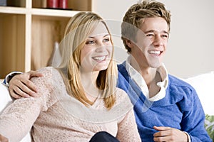 Young Couple Sitting On Sofa Together Watching TV