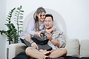 A young couple sitting on a sofa watching pictures in the camera