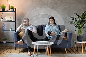 Young Couple Sitting on the Sofa. The Woman Tears Up The Photo. Family Conflict.