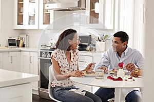 Young couple sitting at the table in their kitchen eating a romantic meal together, selective focus