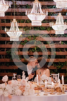 A young couple is sitting at a table at a wedding in the evening. Wedding decorations